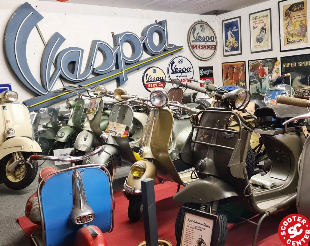 large Vespa collection in one room with an original Vespa sign