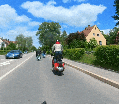 Standing man on a red Vespa