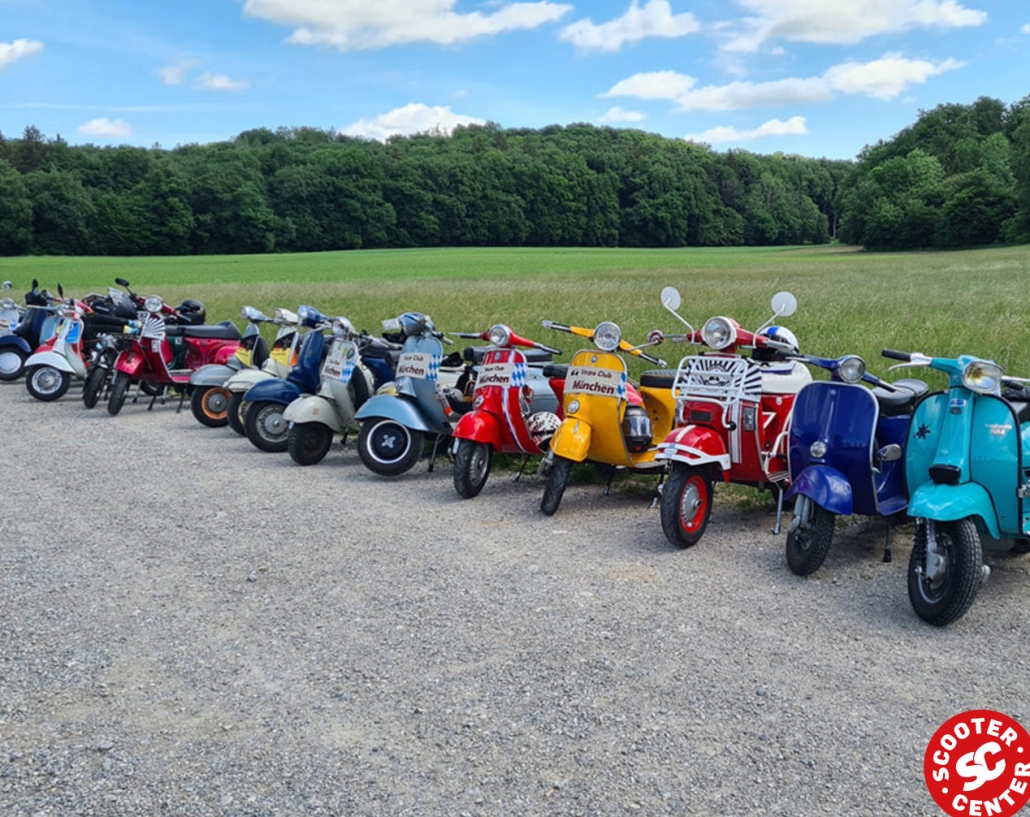 a row of Vespas in front of a green meadow